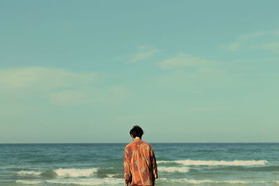 Rear view of woman by sea against sky