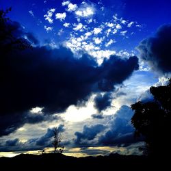 Silhouette of trees against cloudy sky