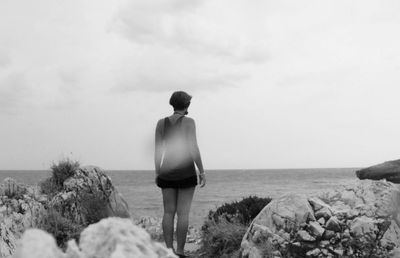 Rear view of man standing on beach against sky