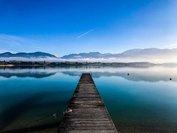 Pier over lake against blue sky
