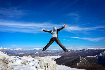 Low angle view of man standing on mountain against sky