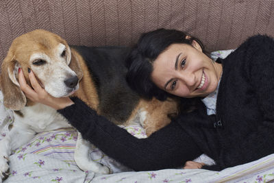 Young woman and her beagle dog, in bed