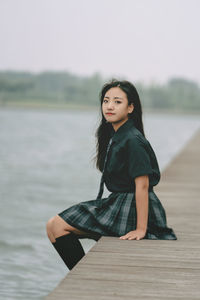 Damsel in uniform by a lake on a cloudy day