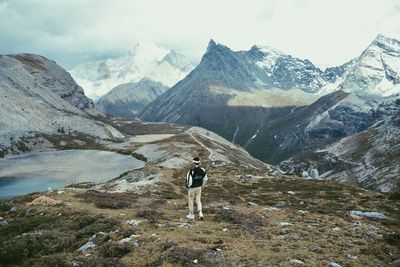 Rear view of man standing on mountain against sky