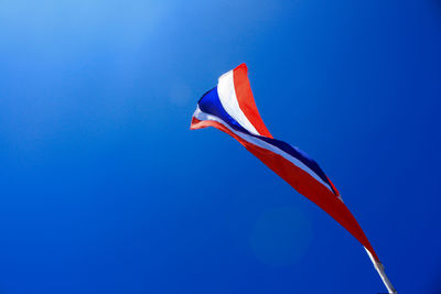 Low angle view of thai flag against clear blue sky