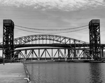 Bridge over river against sky in city