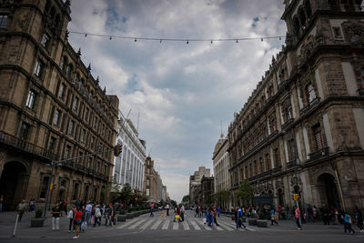 Group of people walking on road along buildings