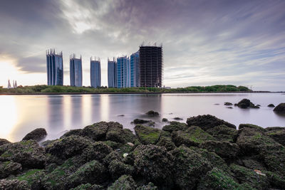 Sea by modern buildings against sky in city