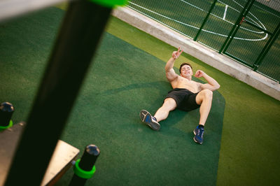 Portrait of muscular man gesturing while lying down on field