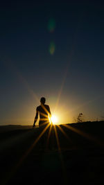 Silhouette man standing on street against sky during sunset