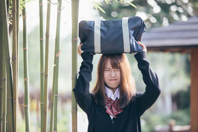 Young woman carrying bag on head outdoors