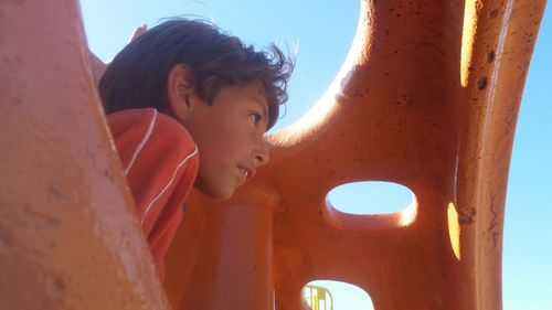 Boy looking away by outdoor play equipment in park