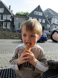 Portrait of boy with ice cream against buildings