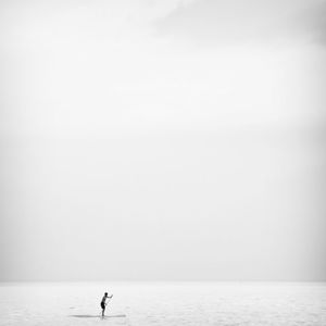 Silhouette person standing on sea against clear sky