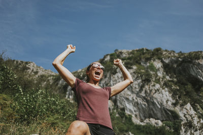 Full length of happy young woman with arms raised