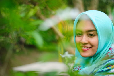 Close-up of woman wearing hijab looking at flower in park