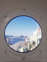 Buildings seen through glass window against clear blue sky