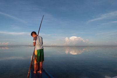 Man with fishing net on beach against sky