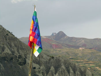 Multi colored flag on mountain range against sky