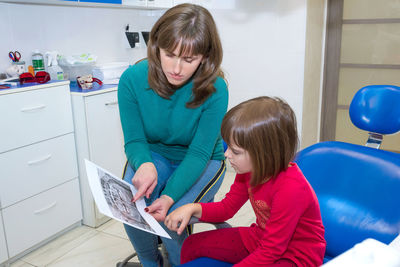 Side view of mother using digital tablet while sitting at home