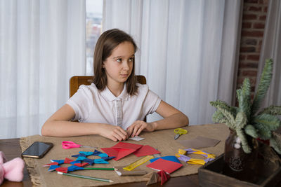 A beautiful teenage girl makes origami