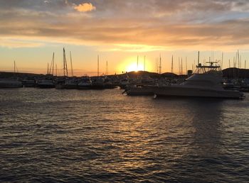 Boats moored at harbor against sky during sunset