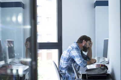 Side view of man looking through window