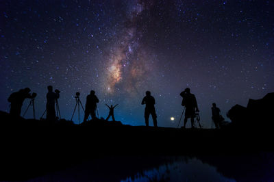 Silhouette people standing against sky at night