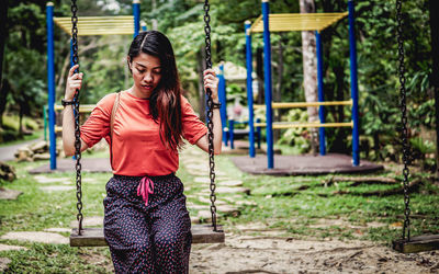 Portrait of woman standing on swing at playground