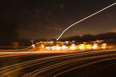 Light trails on road against sky at night