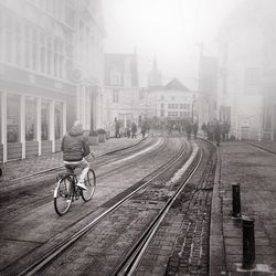 Rear view of man cycling on street in foggy weather