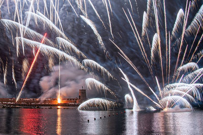 Firework display over river at night