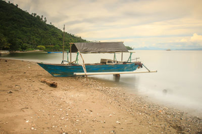 Boat moored on beach against sky