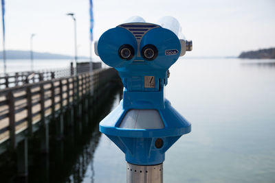 Close-up of coin-operated binoculars against sea