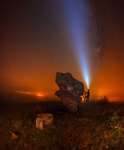 Man climbing on rock formation against star field