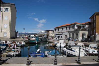 Sailboats moored at harbor against buildings in city