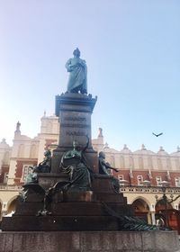 Statue in city against clear sky