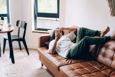 Attractive hispanic woman lies relaxed on the sofa in the living room in a comfortable position.