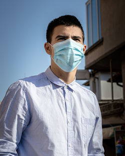 Portrait of young man standing against blue wall