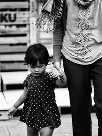 Midsection of mother holding daughter hand on footpath