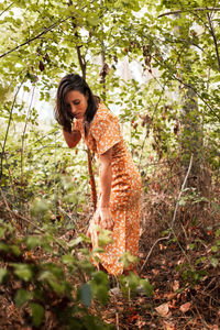 Woman standing by tree in forest