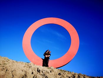 Low angle view of man standing against clear blue sky