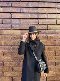 Portrait of young woman standing against wall