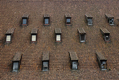 Old roof with roof tiles, attic and various windows