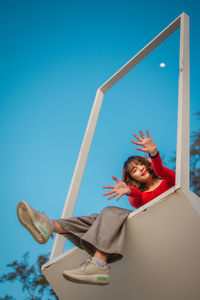 Low angle view of happy girl against blue sky