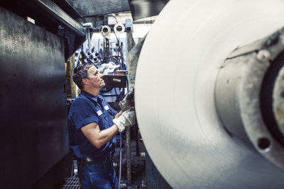 Worker using machine while working in steel mill