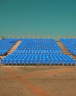 Empty seats in row against clear blue sky