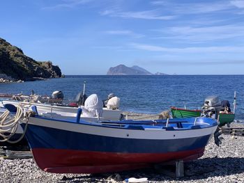 Boat moored on beach against sky