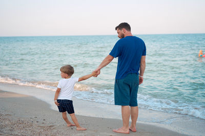 Full length of father and son standing on beach