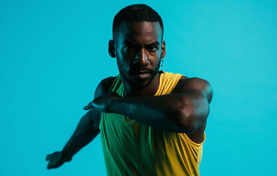 Portrait of young man standing against blue background